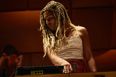 Woman wearing a white top and blonde braided hair performs at an event